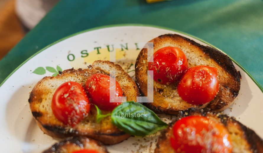 bruschetta, Italian recipe of the Mediterranean diet. Toasted bread with cherry tomatoes, basil and extra virgin olive oil. Typical Apulian food, Ostuni is written on the plate.
