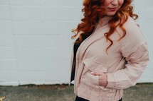 a redhead woman with her hands in her pockets 