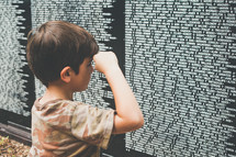 a child showing respect  at the Vietnam veterans memorial wall 