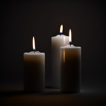 3 lit candles on a dark background