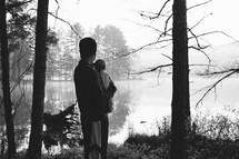 a father holding his baby and view of a lake 