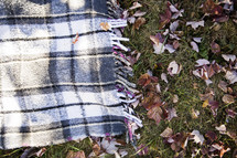 a blanket in the grass and fall leaves 