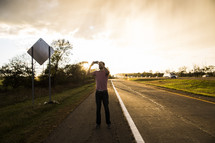 man taking pictures on the side of a road 