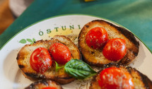 bruschetta, Italian recipe of the Mediterranean diet. Toasted bread with cherry tomatoes, basil and extra virgin olive oil. Typical Apulian food, Ostuni is written on the plate.