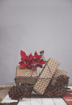 pine cones, presents, and poinsettia in a basket 