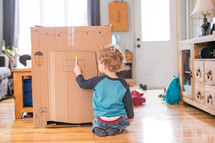 toddler boy playing with a cardboard box 