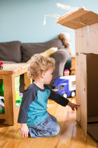 toddler boy playing with a cardboard box 