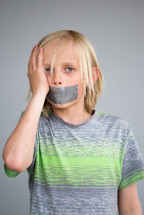 a boy child with duct tape over his mouth 