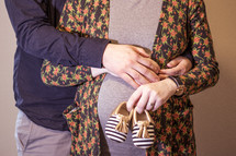 expecting couple holding infant shoes 