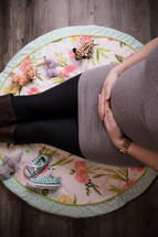 pregnant mother sitting on a nursery room rug 