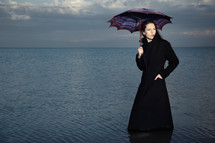 a woman holding an umbrella standing in water 
