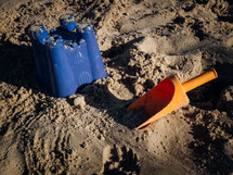 a children's trowel shovel and sandcastle bucket on the beach