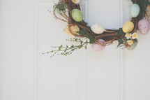 an Easter wreath hanging on a door 