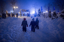 kids playing in the snow at an outdoor festival at night 