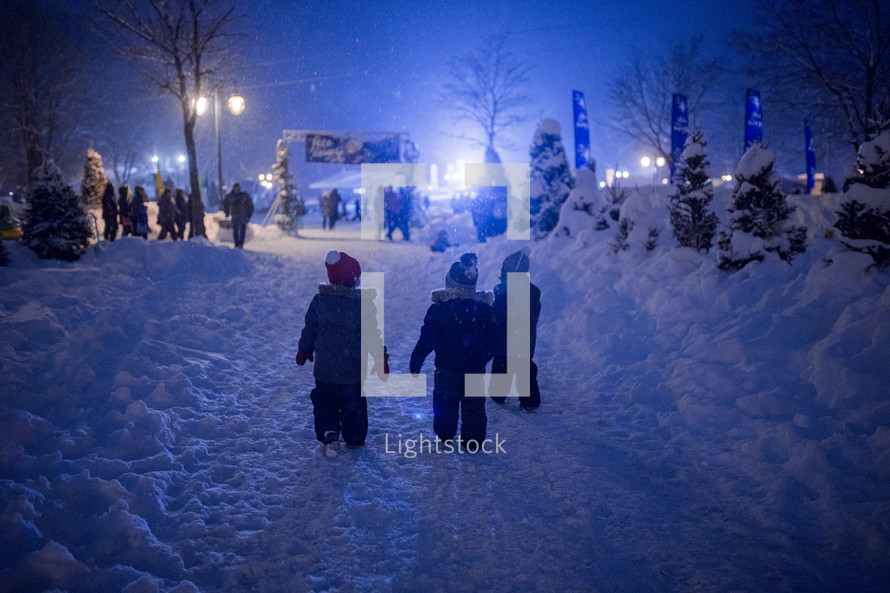kids playing in the snow at an outdoor festival at night 