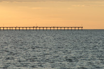 a pier in the ocean at sunset