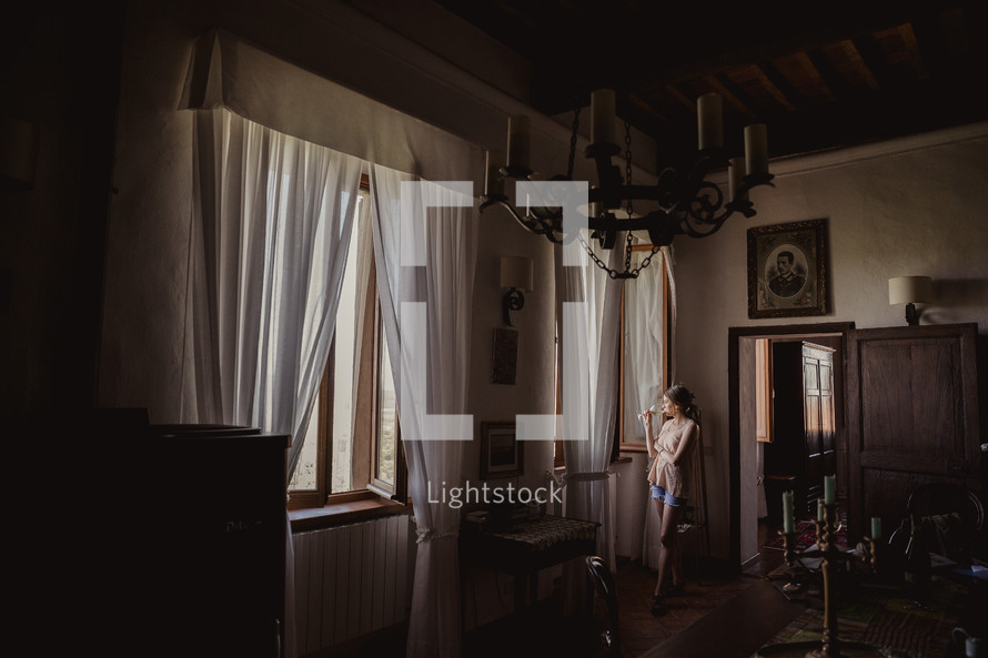 A woman looking out a window in a villa in Italy