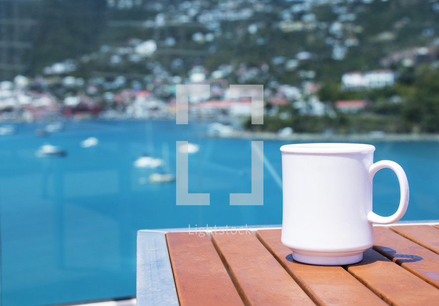 coffee mug on a table and view of boats in a bay 