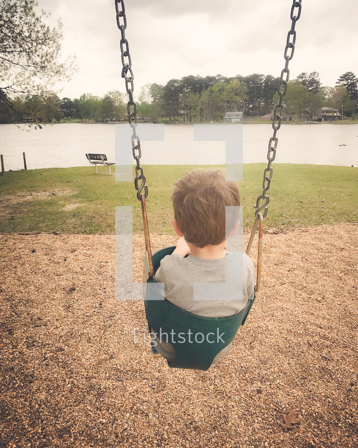toddler boy on a swing at a park 