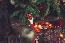 toddler playing with an ornament on a tree