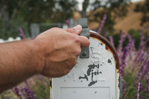 man opening a rusty mailbox 