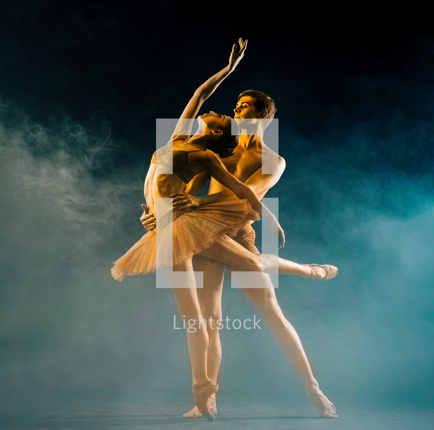 Professional, emotional ballet dancers on dark scene performed by golden couple with body-art. Shining gold skin. Pair depicts love and passion on stage in smoke