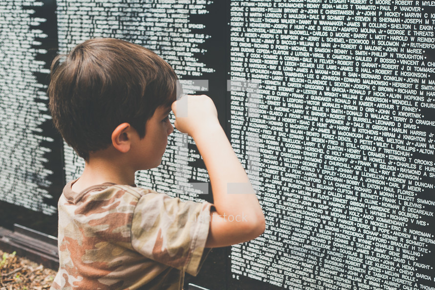 a child showing respect  at the Vietnam veterans memorial wall 