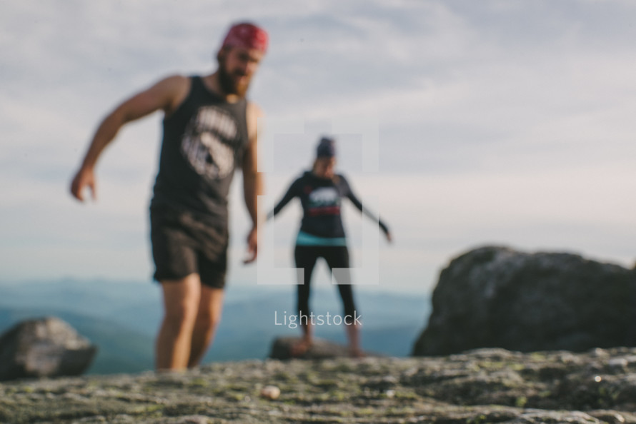 Two people walking on a rocky mountaintop.