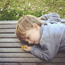 toddler boy picking flowers and resting on a park bench 