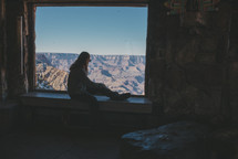 woman sitting in a window sill looking out at canyons 
