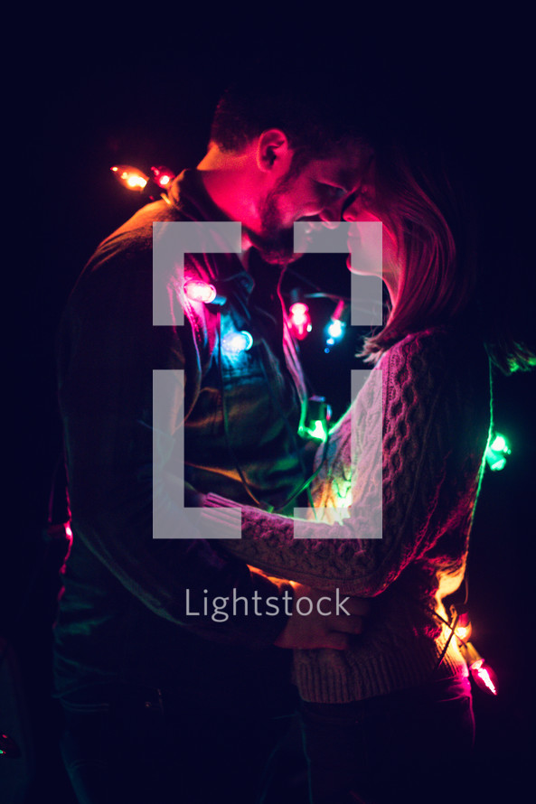 couple wrapped in Christmas lights 