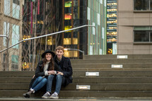 a couple sitting on concrete steps outdoors 