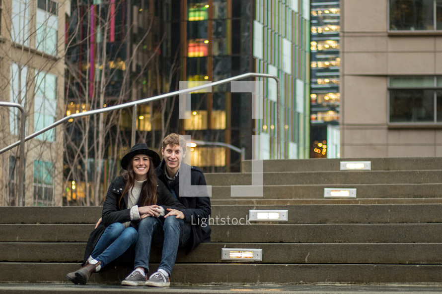 a couple sitting on concrete steps outdoors 