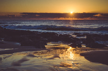 The sunrise reflected on a rocky beach