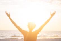 blurry image of a man with raised hands standing on a beach 
