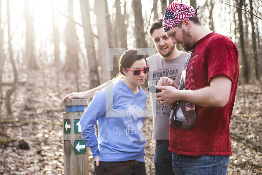 friends looking at a map on a cellphone before a hike 
