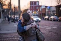 female friends hugging on a sidewalk 