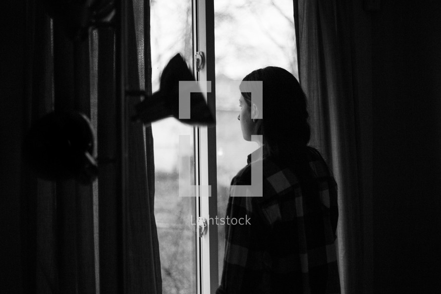 a woman looking out a sliding glass door 