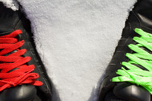 red and green shoe laces on black sneakers standing in snow