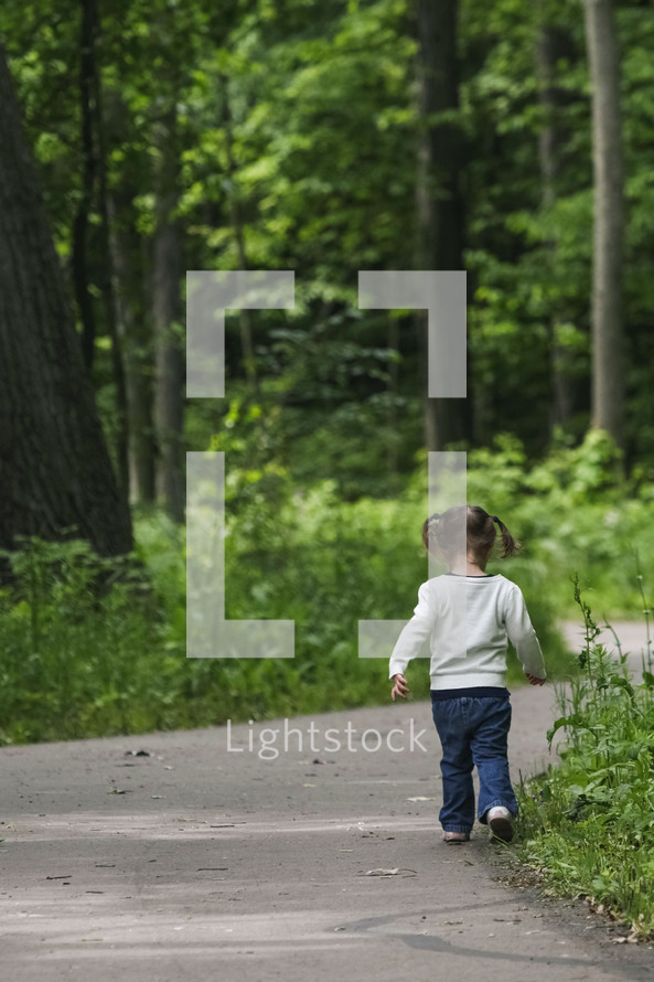 toddler girl walking on a path 