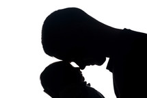 silhouette of a father cradling a newborn 