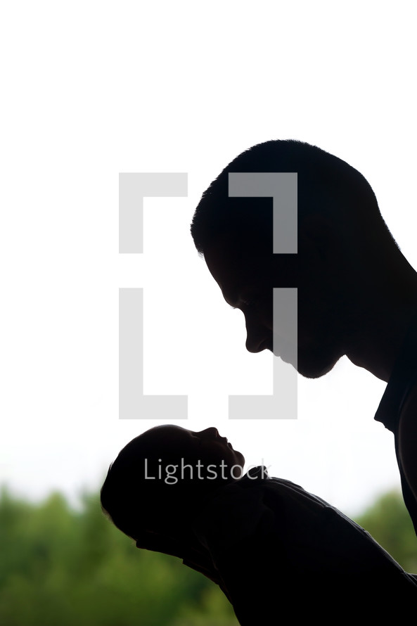 silhouette of a father holding newborn 