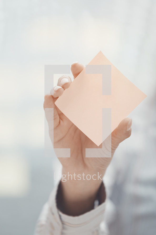 woman holding up a blank sticky note 