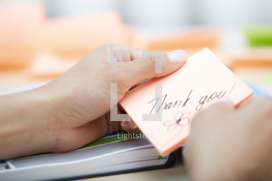 a woman holding a sticky note with the words thank you 