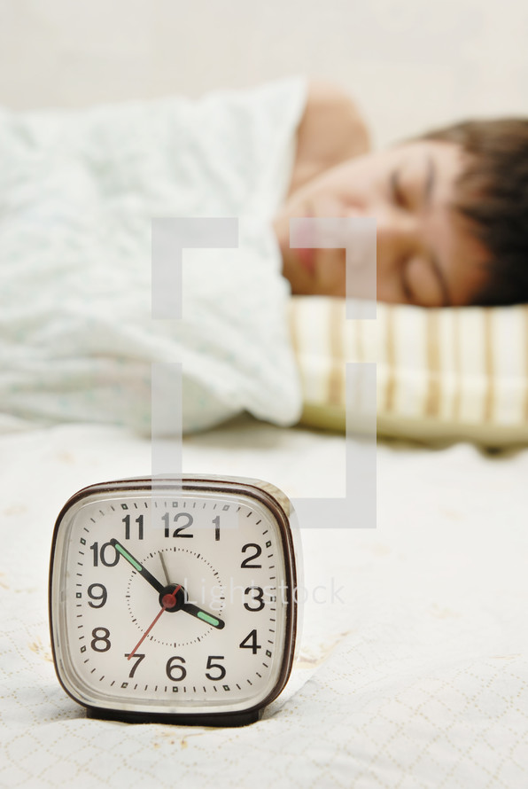 sleeping boy next to an alarm clock 