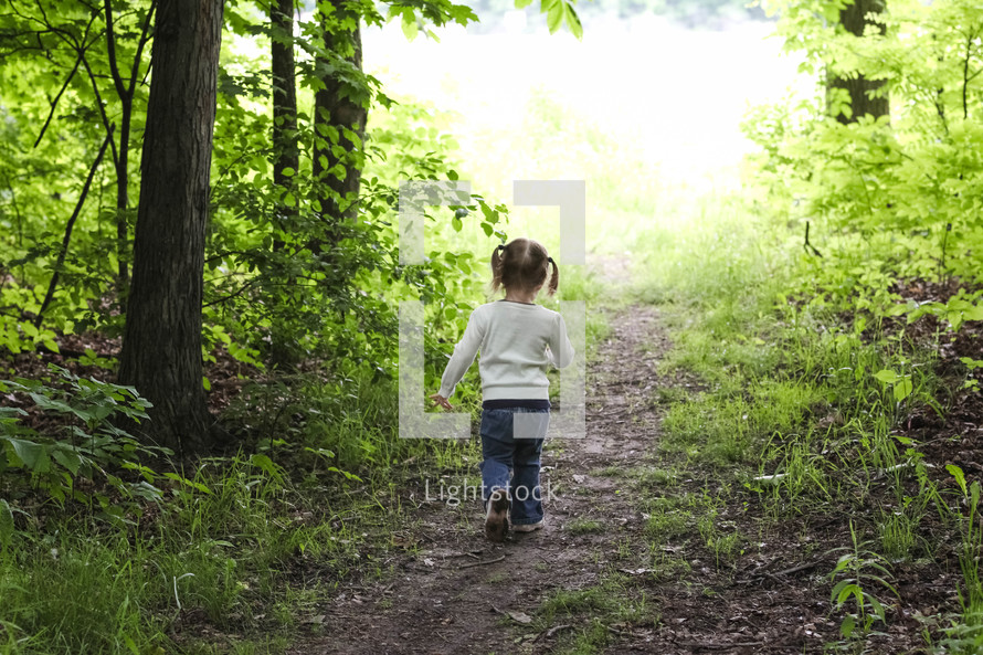 a toddler girl walking on a path 