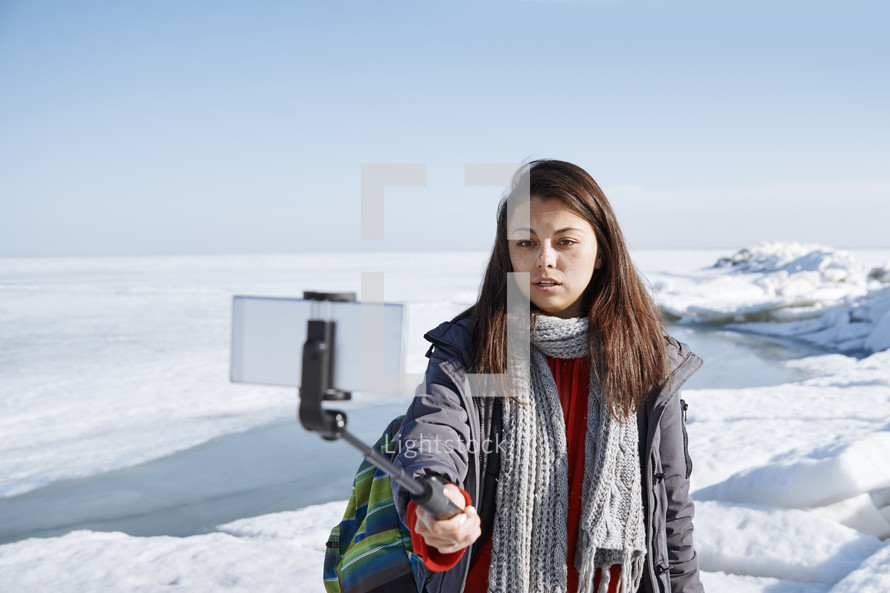 a young woman exploring a snow covered landscape and taking a selfie 