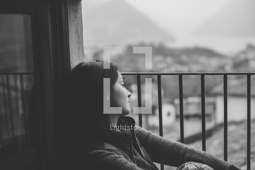A young woman gazing out a barred window in black and white