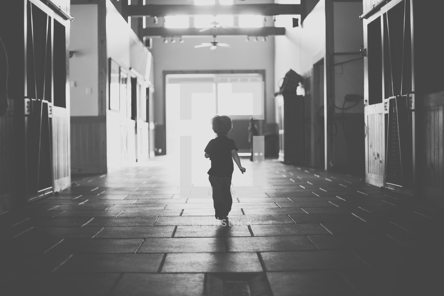 toddler boy running in a stable 