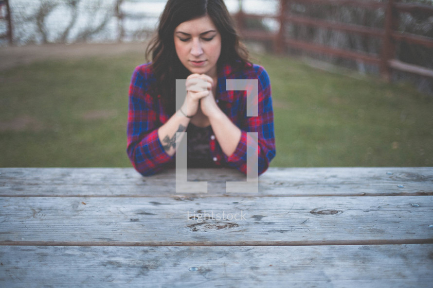 A woman praying outdoors. 